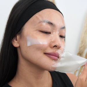 Person applying a face mask with eyes closed.