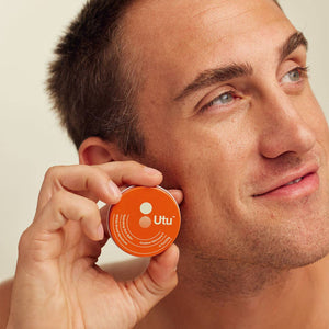 Man holding an orange container with 'Utu' branding close to his face.