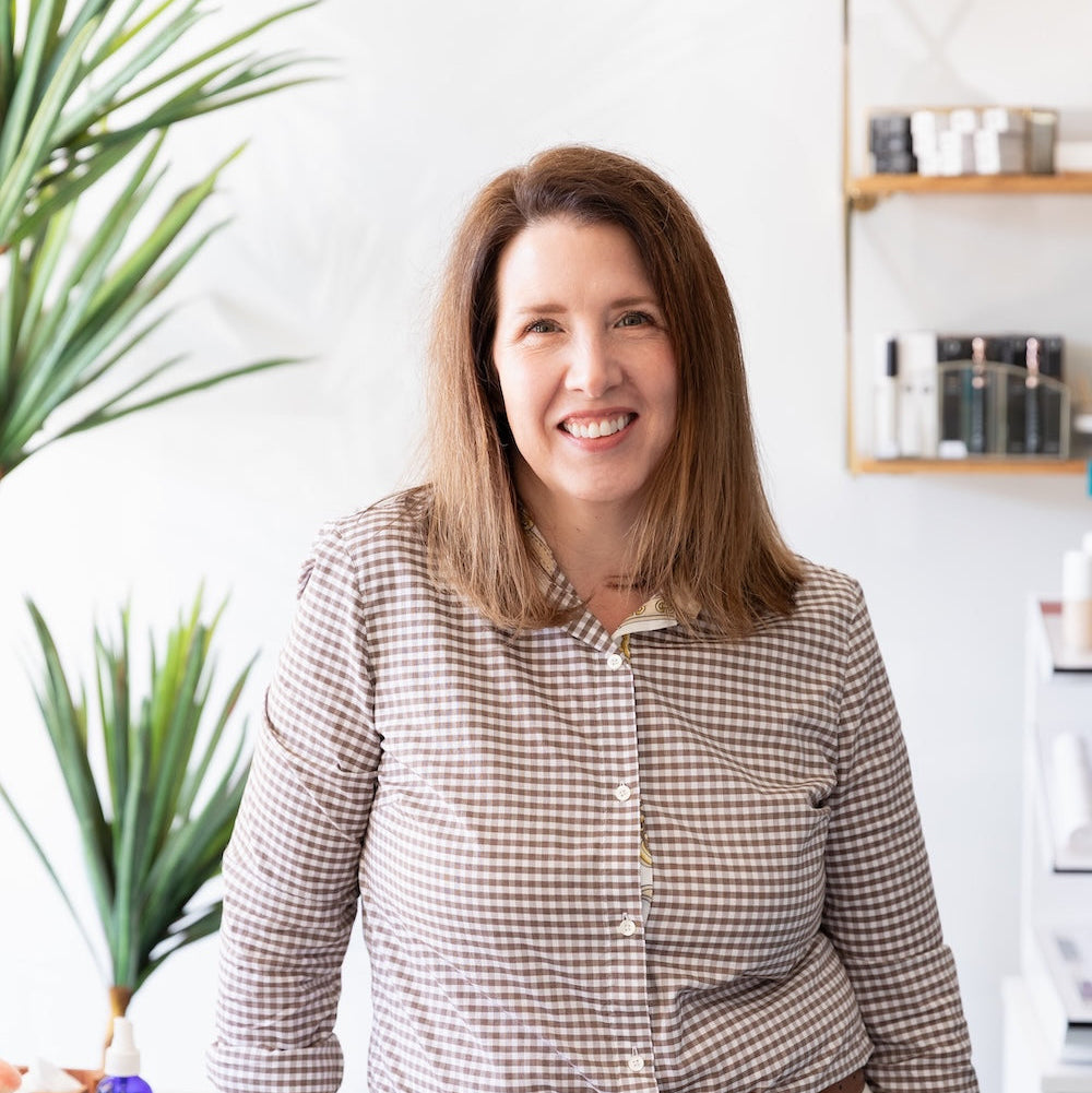 Woman standing in a kitchen with plants and shelves in the background