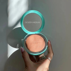 Hand holding a compact powder with 'Sculpted' branding against a neutral background