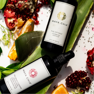 Two bottles of Maya Chia on a decorative background with pomegranate and orange slices.