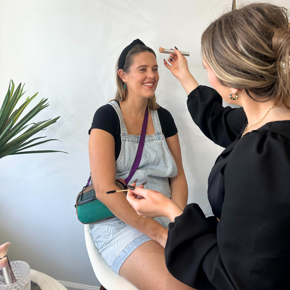 Makeup artist applying makeup to a model in a home setting