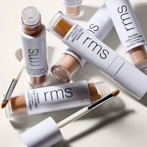 RMS beauty concealer bottles and applicators on a light background