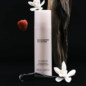 Maison Louis Marie Fleur de Vanille hair and body mist with vanilla pod, flowers, and raspberry on a black background