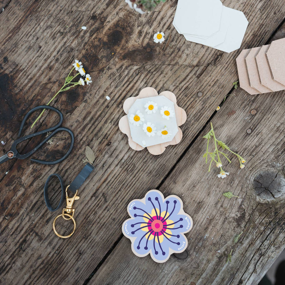 Flowers on a wooden surface with scissors and flowers ready to put in flower press.