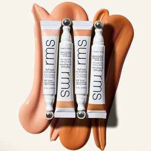 Four RMS beauty skincare tubes on a beige background