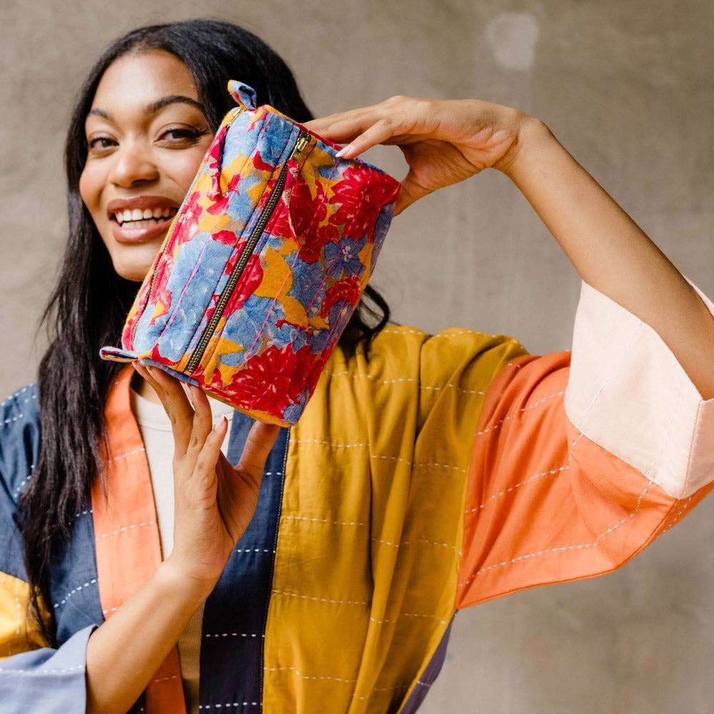 Woman holding a colorful pouch against a neutral background