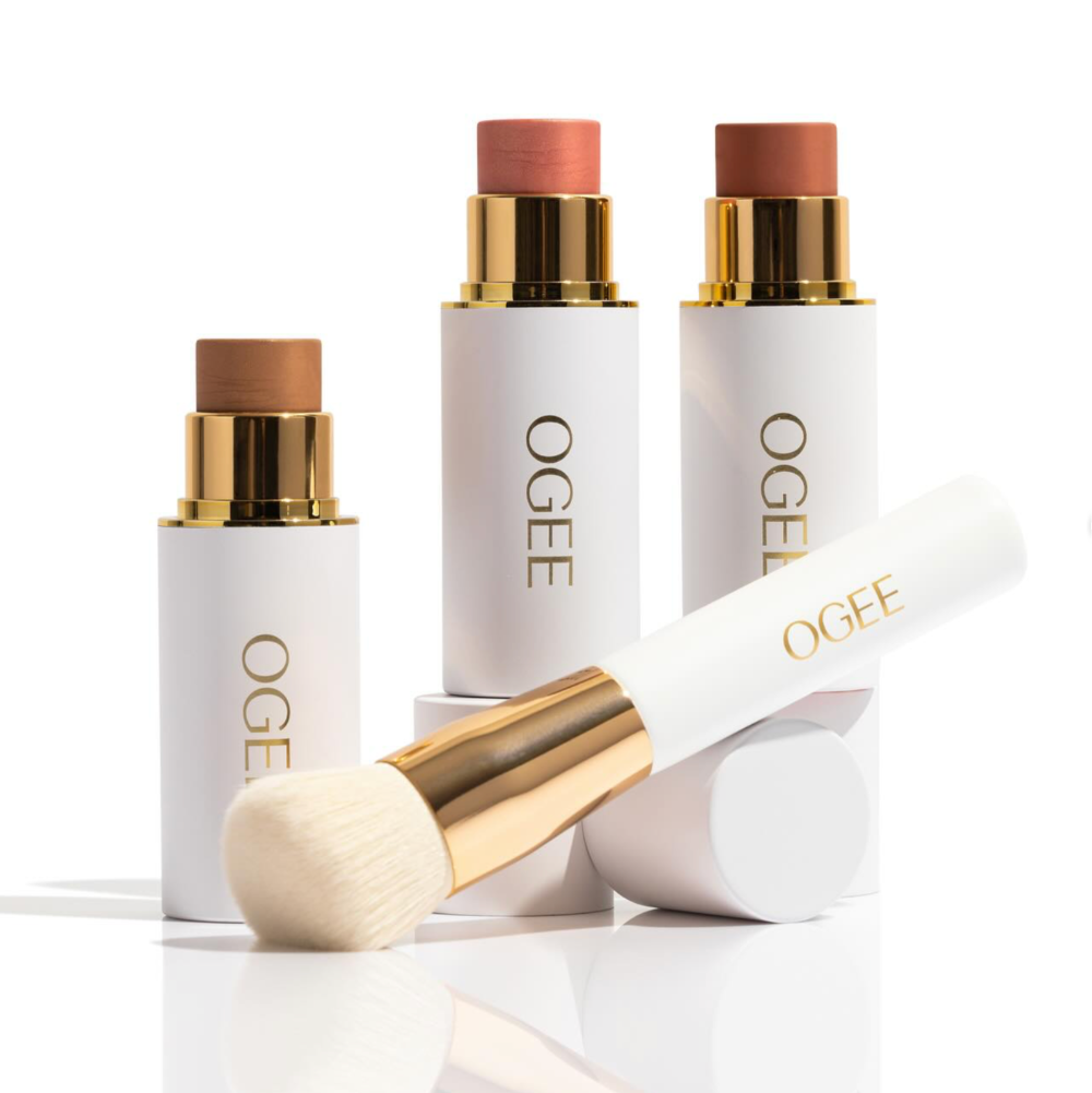 three tubes of makeup with a brush sitting in front