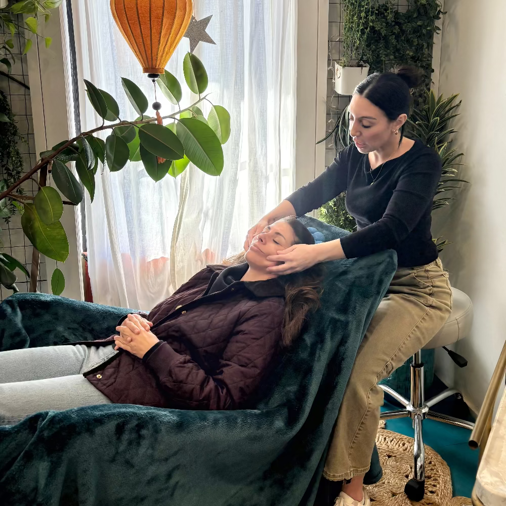 Person receiving a massage in a cozy room with plants and a window.