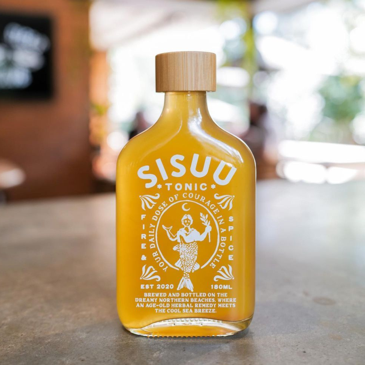 Yellow bottle of SISUU Tonic with a wooden cap on a blurred background