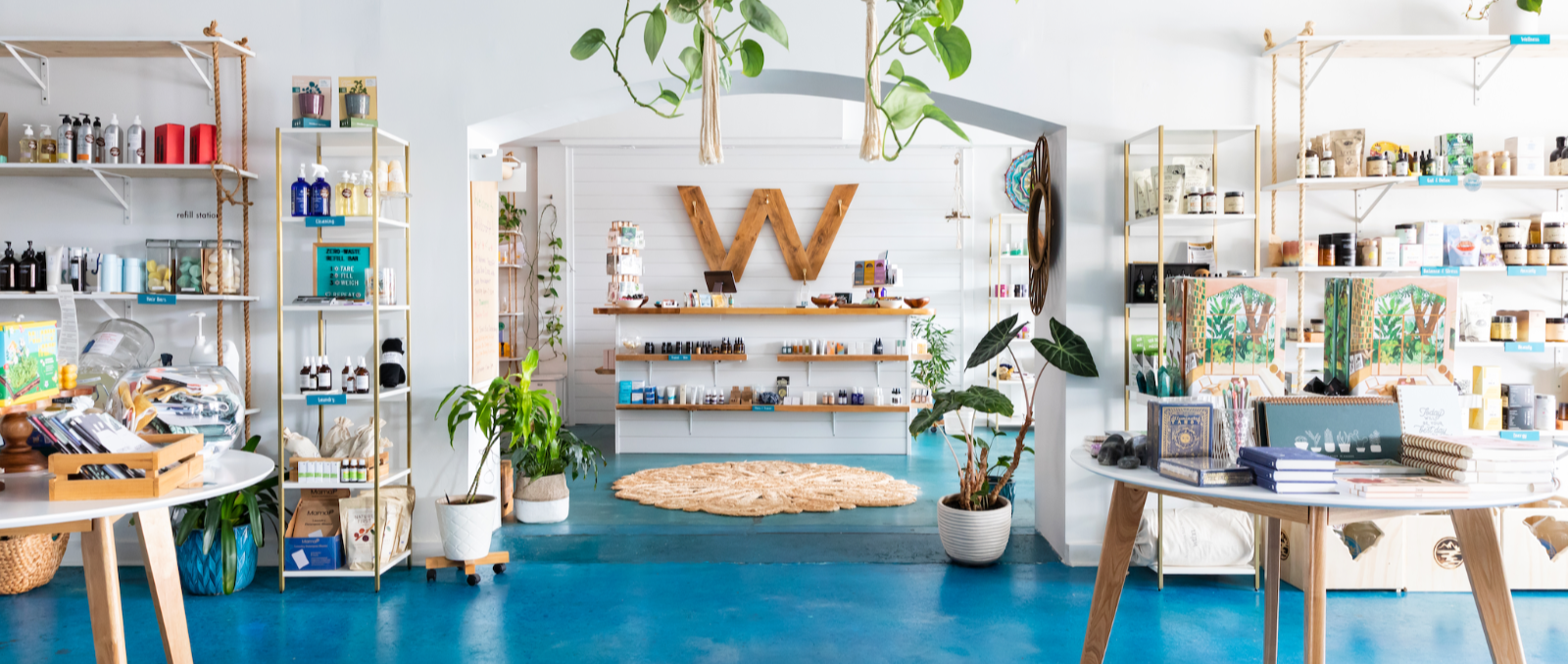 shop image of products with white walls, plants and blue floors