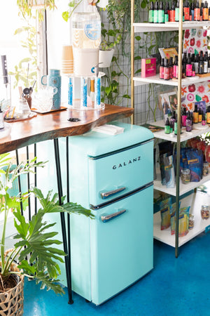 Turquoise refrigerator in a room with shelves and plants