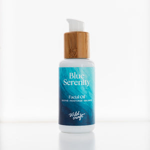 Facial oil bottle labeled 'Blue Serenity' with a bamboo cap on a white background