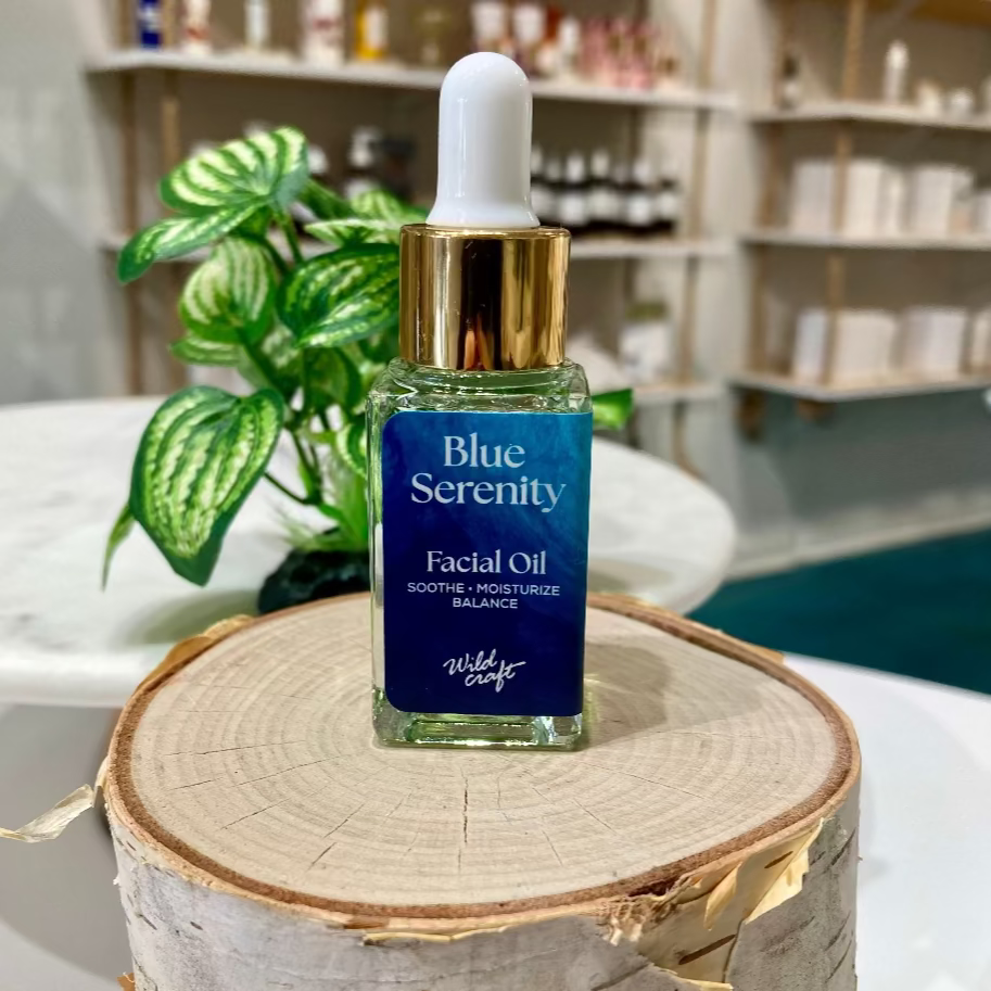 Facial oil bottle labeled 'Blue Serenity' on a wooden block with a blurred background