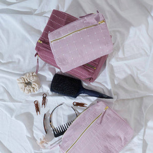 Pink makeup bags with gold zippers on a white fabric background