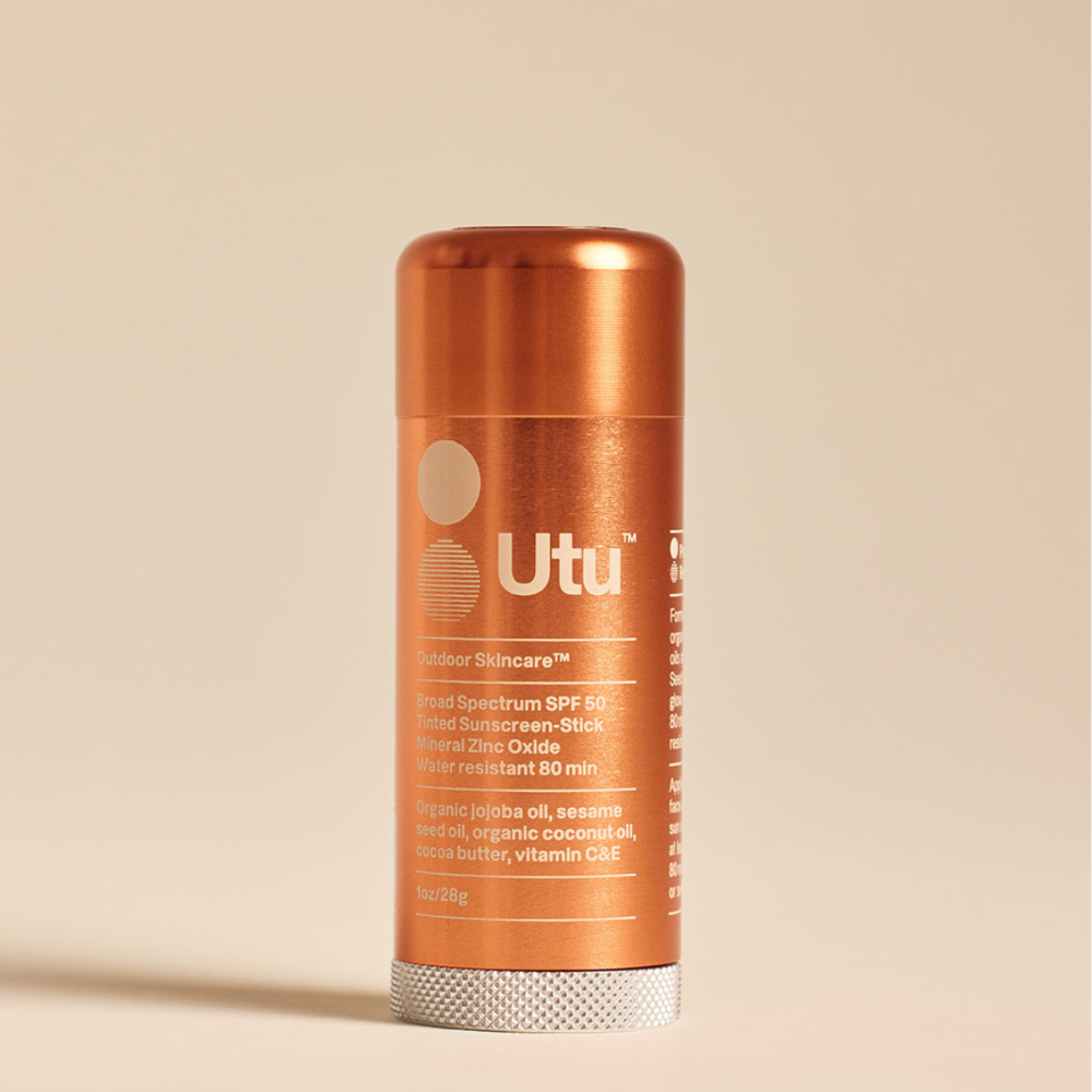 Orange bottle of Utu outdoor skincare product on a beige background