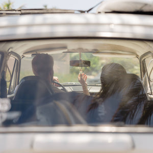 Two people inside a vintage car with a California license plate.