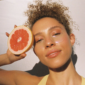 Woman holding a grapefruit near her face with a natural background