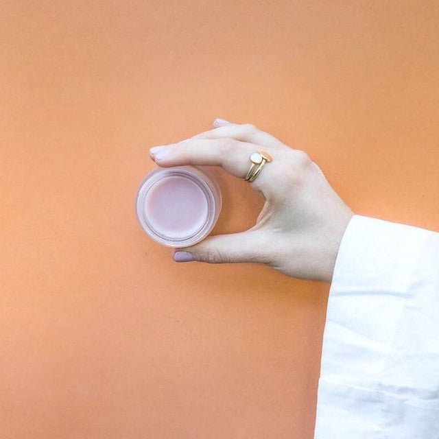 A jar of Leahlani Bless Beauty Balm with a gold lid on a white background.
