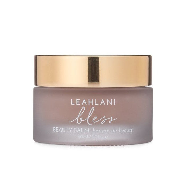 A jar of Leahlani Bless Beauty Balm with a gold lid on a white background.